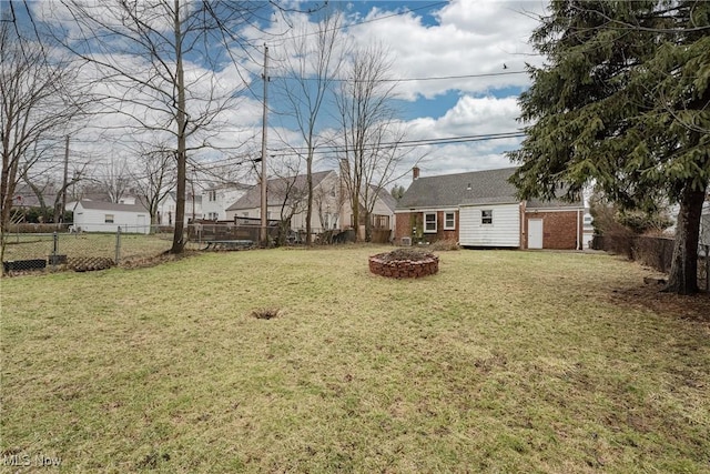 view of yard with a fenced backyard, a fire pit, and an outbuilding