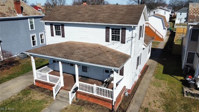 view of front facade with central air condition unit, covered porch, a shingled roof, and a chimney