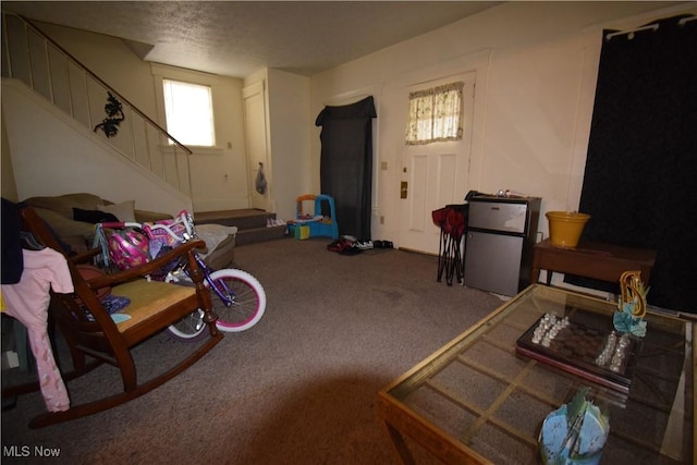 living room with carpet floors, stairway, and a textured ceiling