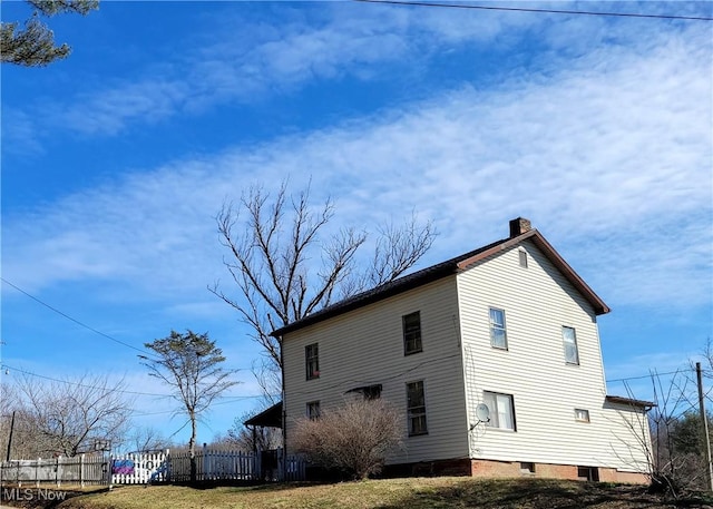 view of property exterior featuring a chimney and fence