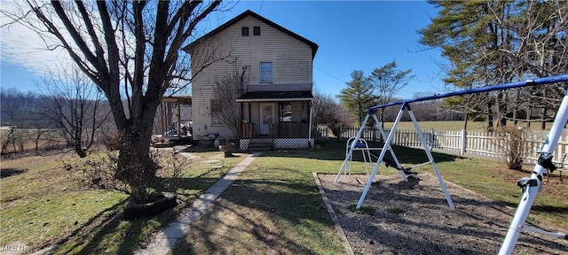 rear view of house with a playground, fence, and a lawn