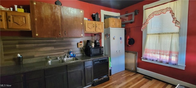 kitchen featuring tasteful backsplash, visible vents, light wood-style floors, black appliances, and a sink