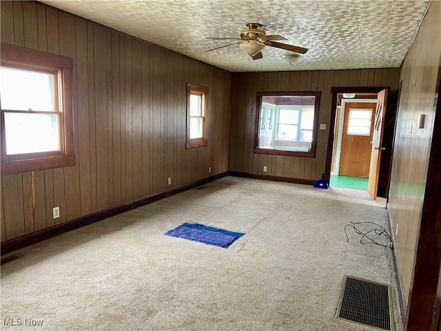 carpeted empty room featuring a ceiling fan, visible vents, and baseboards