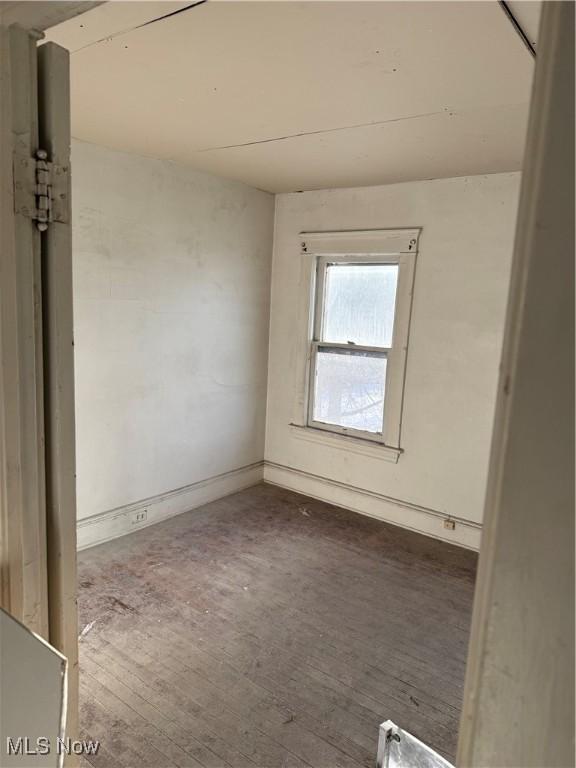 spare room featuring baseboards and dark wood finished floors