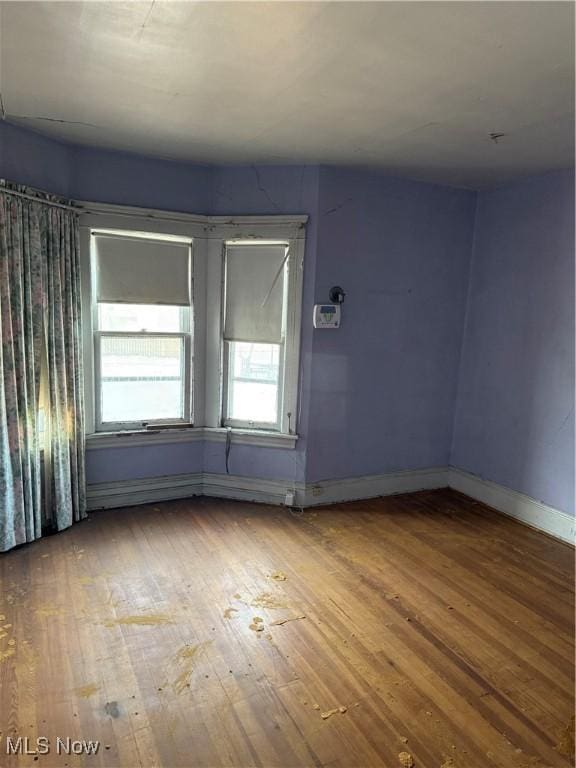 spare room with hardwood / wood-style flooring and baseboards