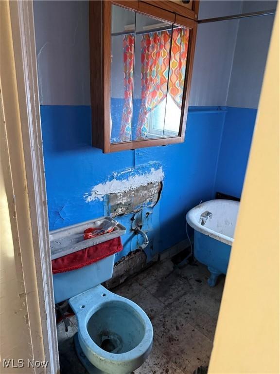 bathroom with a soaking tub and toilet