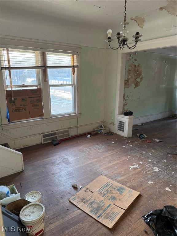 unfurnished dining area featuring a chandelier, wood-type flooring, and visible vents