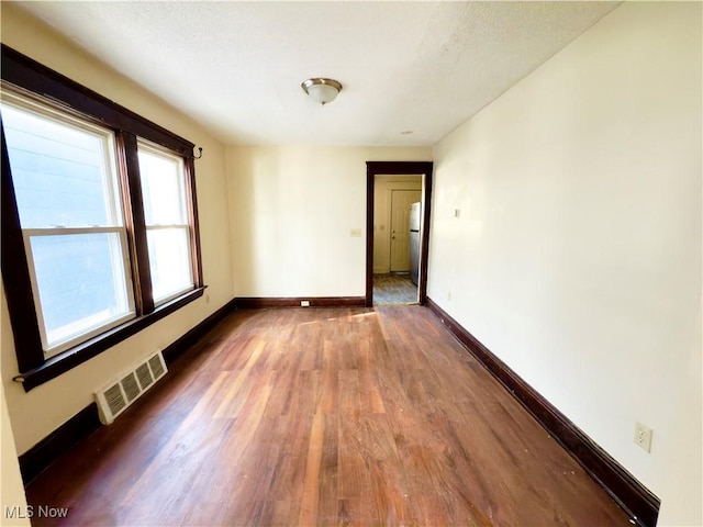 unfurnished room with baseboards, visible vents, and wood finished floors