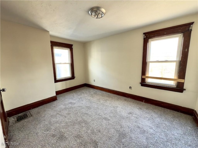 carpeted spare room featuring visible vents and baseboards