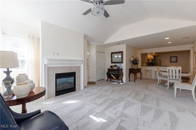 living room with carpet floors, a fireplace, vaulted ceiling, and a ceiling fan