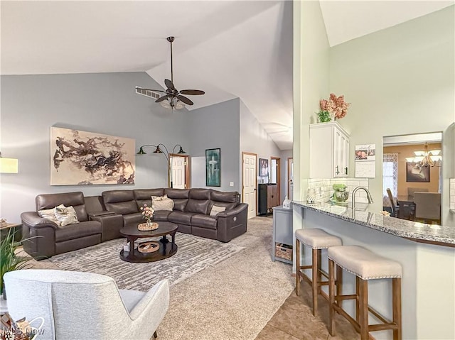 living room with high vaulted ceiling, light carpet, and ceiling fan with notable chandelier