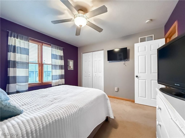 bedroom featuring light carpet, a ceiling fan, baseboards, and a closet