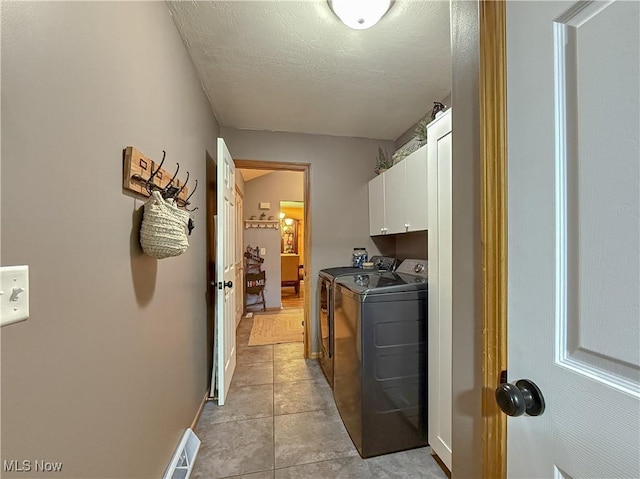 laundry area with cabinet space, light tile patterned floors, visible vents, independent washer and dryer, and a textured ceiling