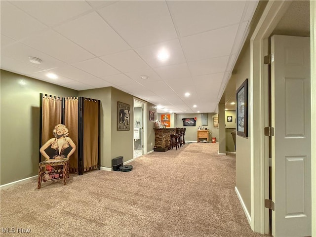 interior space featuring carpet floors, baseboards, a paneled ceiling, and recessed lighting