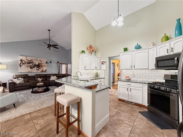 kitchen featuring open floor plan, white cabinets, and gas stove