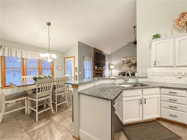 kitchen featuring a peninsula, a sink, white cabinetry, vaulted ceiling, and dishwasher