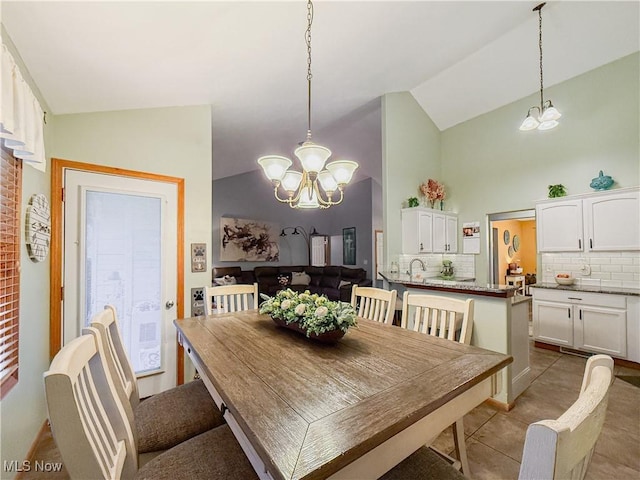 dining area with an inviting chandelier, tile patterned flooring, and vaulted ceiling