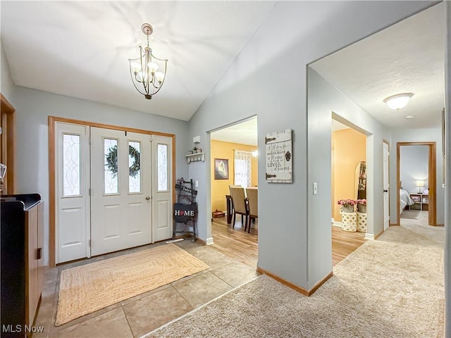 entryway featuring light carpet, baseboards, lofted ceiling, and a notable chandelier