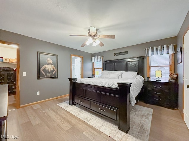 bedroom featuring light wood-type flooring, ceiling fan, multiple windows, and baseboards