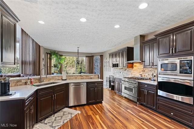 616 Coventry Pl, Amherst, OH 44001 - kitchen featuring stainless steel appliances, a sink, wall chimney range hood, light countertops, and dark brown cabinetry