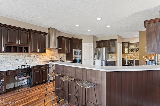 616 Coventry Pl, Amherst, OH 44001 - kitchen featuring wall chimney exhaust hood, light countertops, dark brown cabinetry, and stainless steel appliances