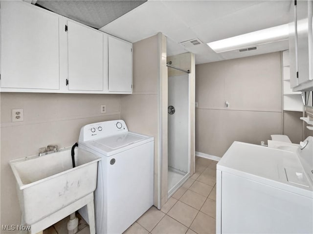 laundry room featuring cabinet space, light tile patterned floors, visible vents, and a sink