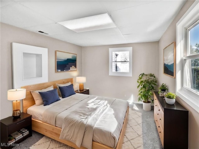 bedroom with carpet, visible vents, and a paneled ceiling