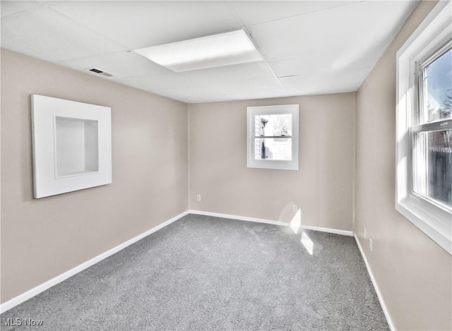 spare room with a drop ceiling, carpet, visible vents, and baseboards