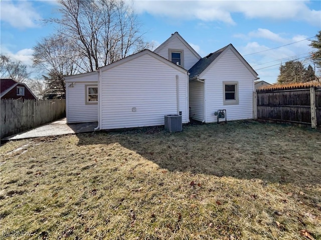 rear view of property with a fenced backyard, central AC unit, and a lawn