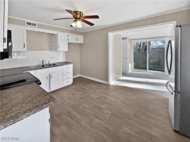 kitchen featuring black range with electric cooktop, a sink, visible vents, freestanding refrigerator, and crown molding