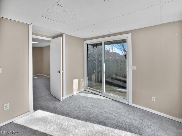 spare room featuring carpet floors, a paneled ceiling, and baseboards