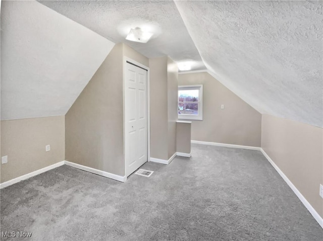 bonus room with carpet floors, baseboards, vaulted ceiling, and a textured ceiling