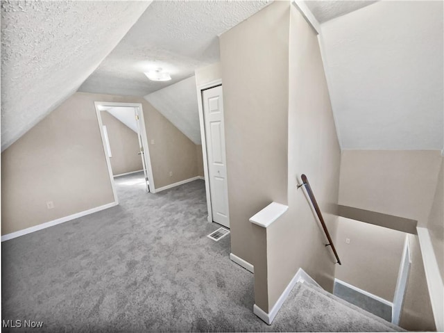 bonus room featuring carpet floors, visible vents, vaulted ceiling, and a textured ceiling