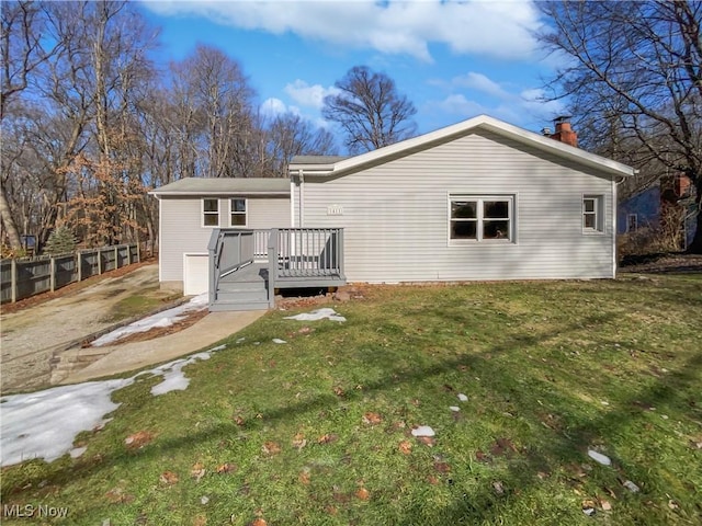 rear view of house with a lawn, fence, and a wooden deck