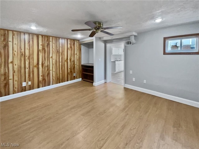 interior space featuring visible vents, wood walls, baseboards, and wood finished floors