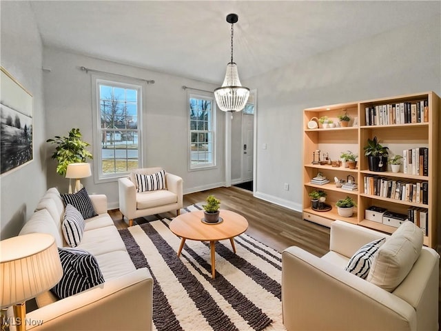 living area featuring a chandelier, baseboards, and wood finished floors