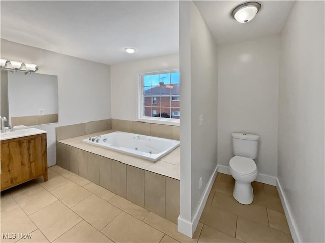 bathroom featuring tile patterned flooring, toilet, vanity, baseboards, and a whirlpool tub