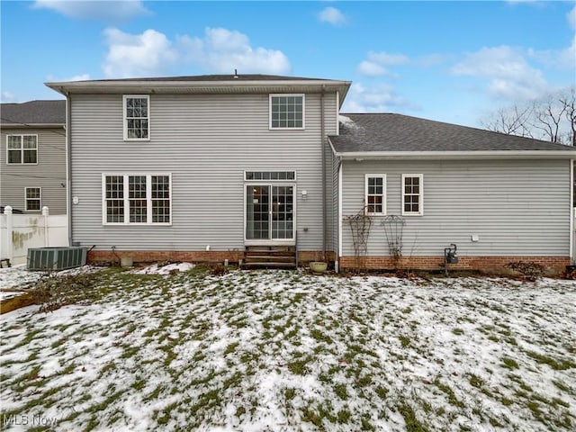 snow covered property featuring entry steps, a shingled roof, and fence