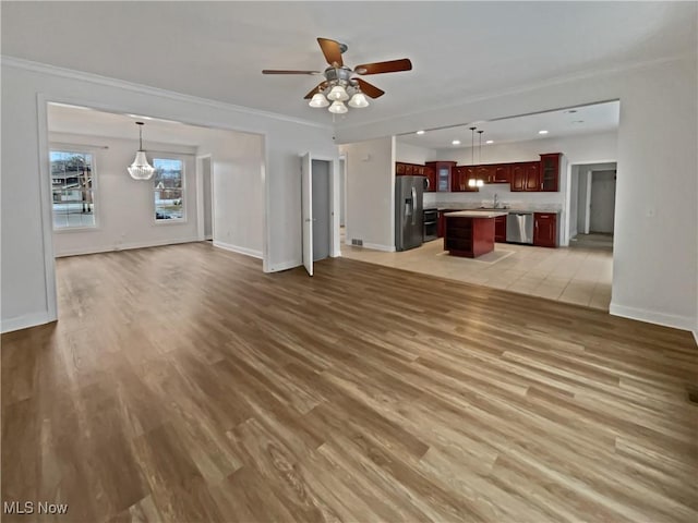 unfurnished living room with light wood-style floors, baseboards, ornamental molding, and a ceiling fan