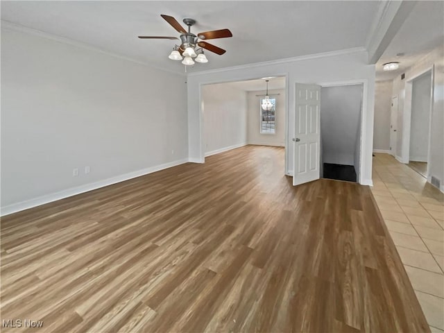 unfurnished living room with ceiling fan with notable chandelier, crown molding, baseboards, and wood finished floors