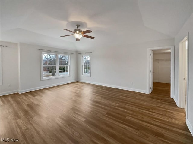 unfurnished room featuring dark wood-style floors, ceiling fan, baseboards, and vaulted ceiling