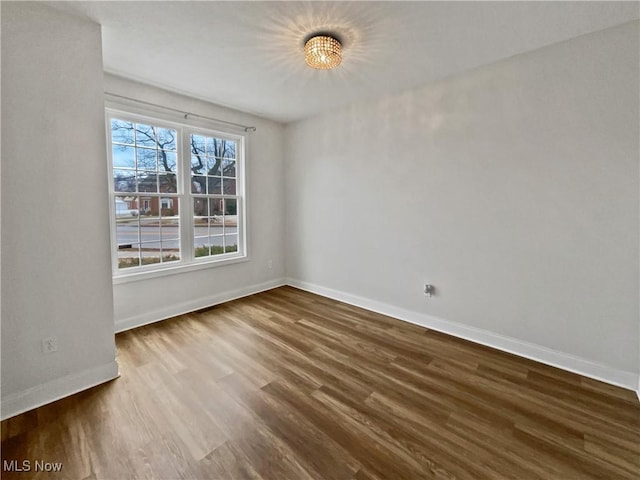 empty room featuring baseboards and dark wood-style flooring