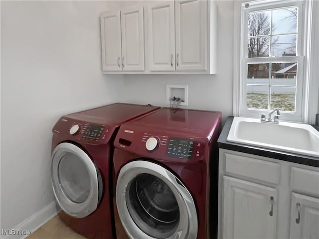 washroom with baseboards, cabinet space, a sink, and washing machine and clothes dryer