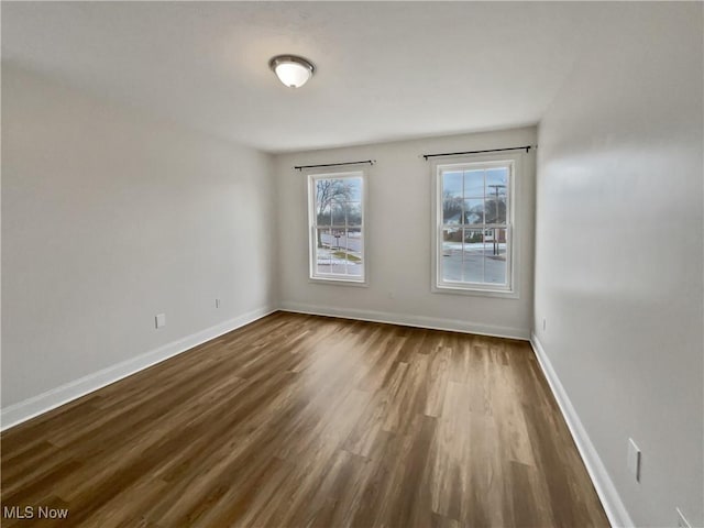 spare room with dark wood-type flooring and baseboards