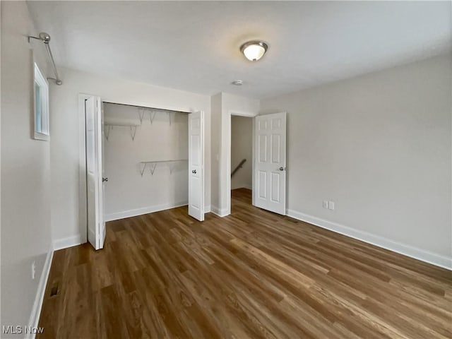 unfurnished bedroom with a closet, baseboards, and wood finished floors