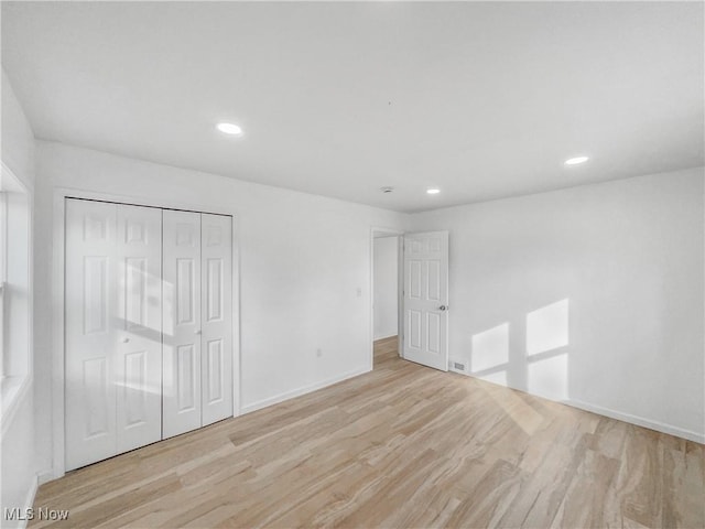 unfurnished bedroom with baseboards, a closet, wood finished floors, and recessed lighting