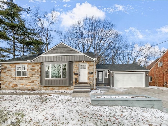 view of front of home featuring driveway, stone siding, a garage, and board and batten siding