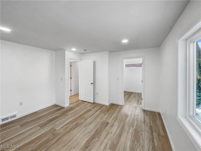 empty room with wood finished floors, visible vents, and baseboards