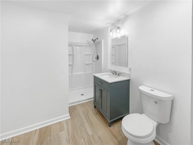 bathroom featuring toilet, a stall shower, baseboards, and wood finished floors