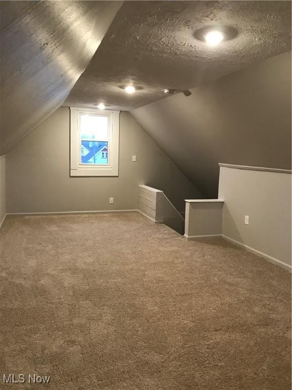 bonus room with a textured ceiling, carpet floors, lofted ceiling, and baseboards